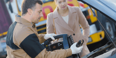 Man jump starting a car, and providing a women roadside assistance